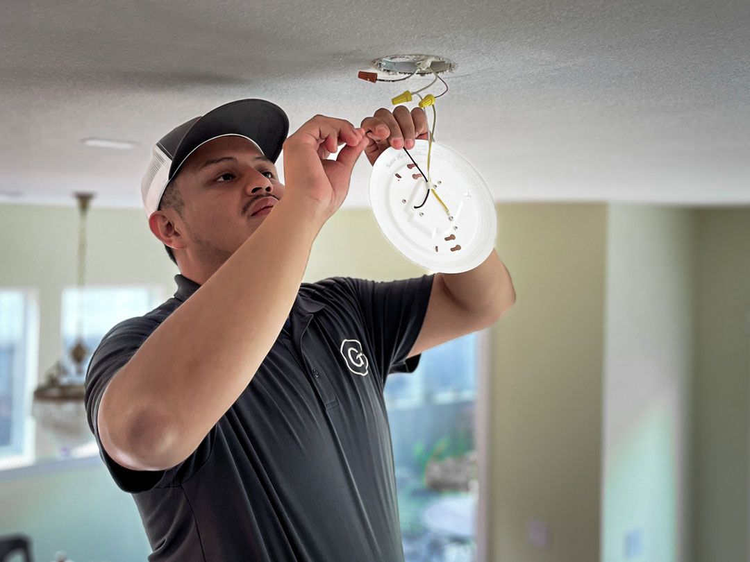 Electrician installing a light fixture on a ceiling